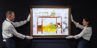 Two people hold up a painting